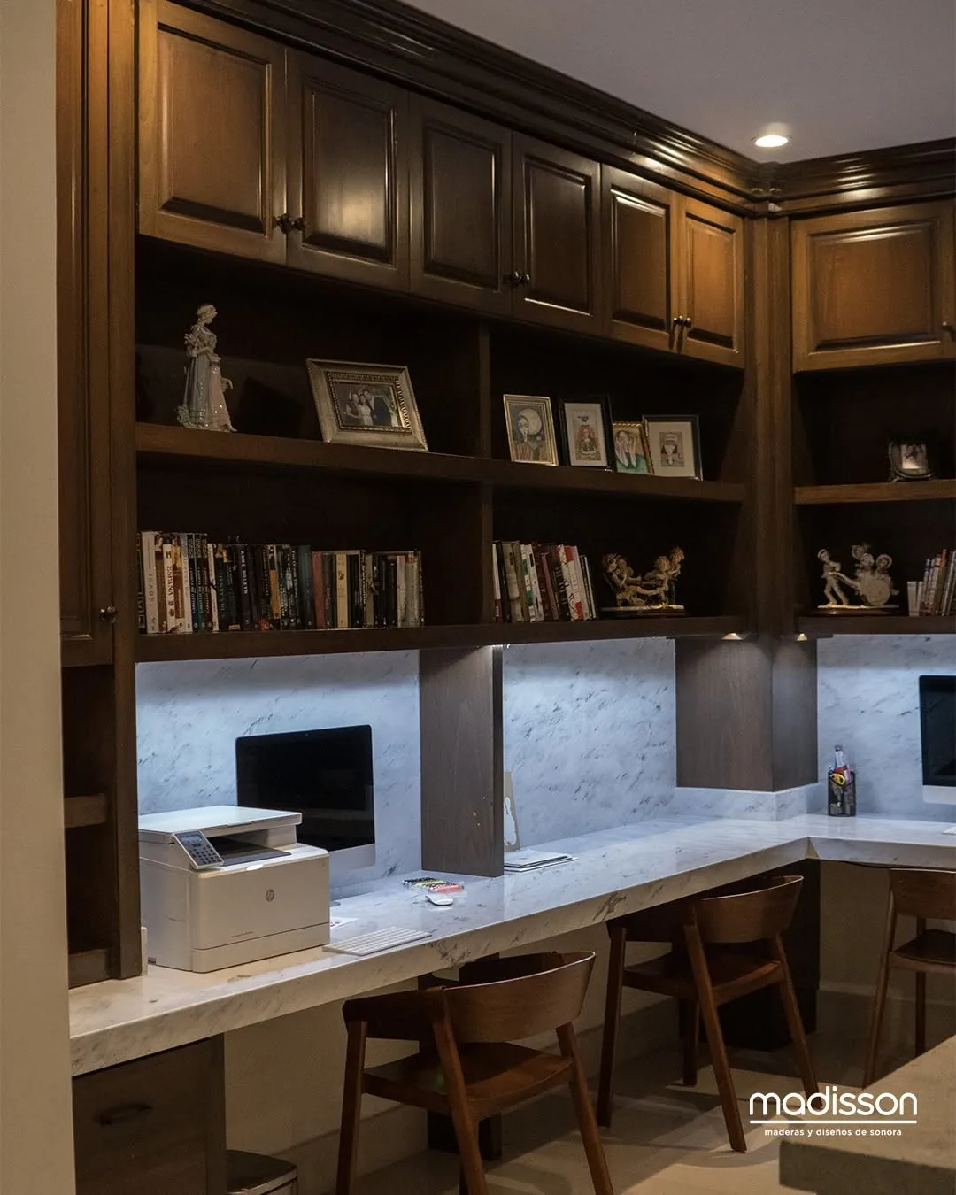 Área de estudio con libreros de madera, repisas iluminadas y cubierta de mármol